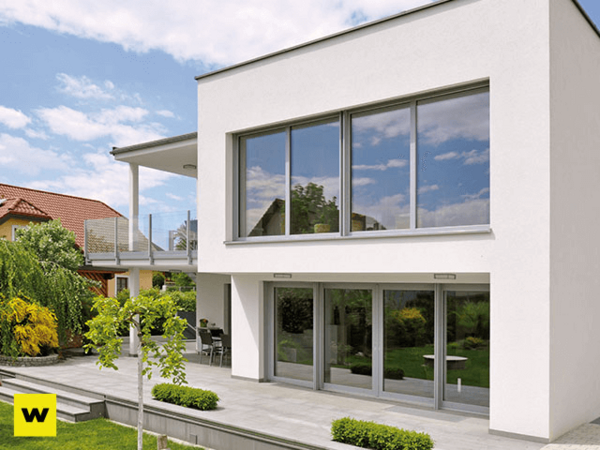 Modernes Einfamilienhaus mit großer Fensterfront und Terrasse im grünen Garten.